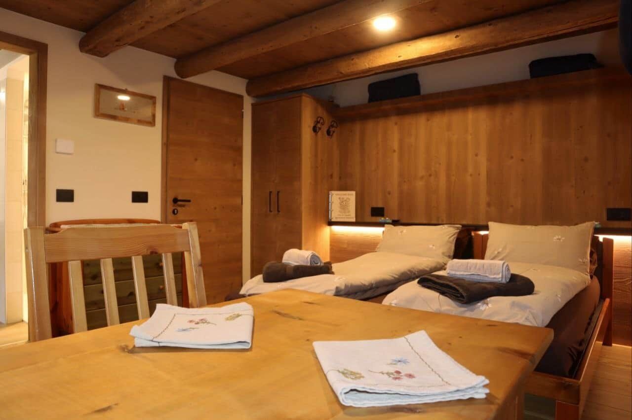 Una habitación con estructura de madera, una cama, una mesa y una silla.