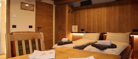 Una habitación con estructura de madera, una cama, una mesa y una silla.