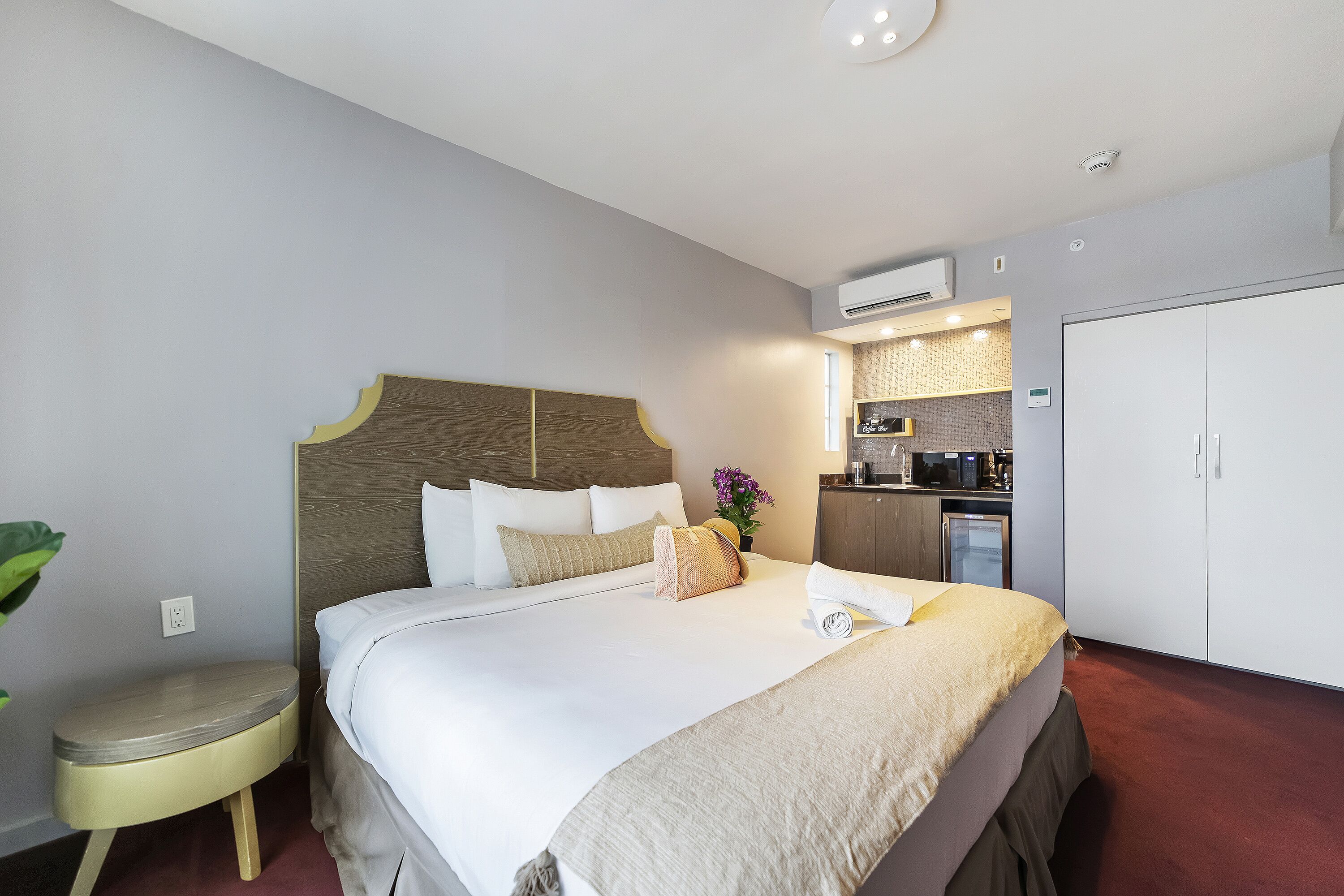 Ein Hotelzimmer mit Bett, Nachttisch und einer Küchenzeile.