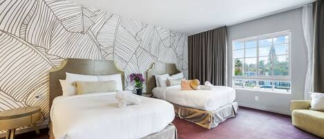 A hotel room with two beds, a large window, and a patterned wall.