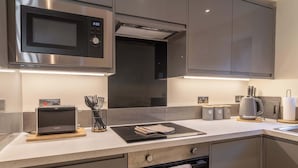 Una cucina moderna con forno a microonde, tostapane e bollitore integrati.