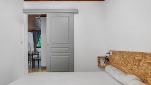 Un dormitorio con una cama, cabecera de madera, una puerta y vistas a un comedor.