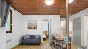 Un interior moderno con techo de madera, un sofá, una mesa de comedor con sillas y una zona de cocina.