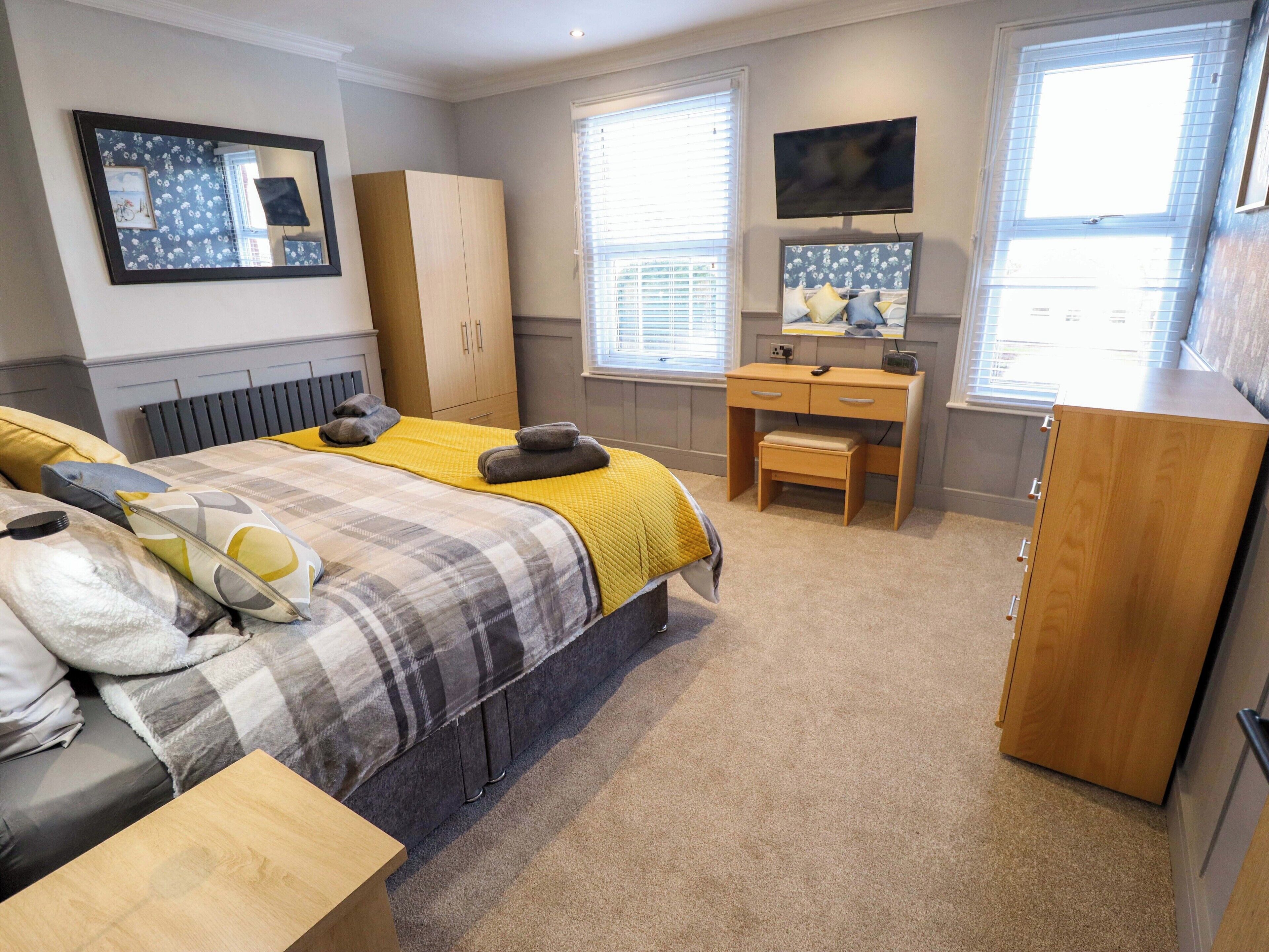 A bedroom with a bed, a desk, a wardrobe, and a TV.