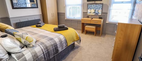 A bedroom with a bed, a desk, a wardrobe, and a TV.