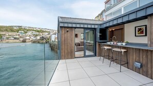 Una cucina esterna moderna con vista sul mare e su una città sullo sfondo.