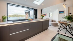 Una cucina moderna con una grande isola, lucernari e vista sull'acqua.