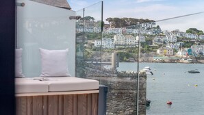 Un balcone con angolo relax imbottito e vista libera su un porto con barche ed edifici.