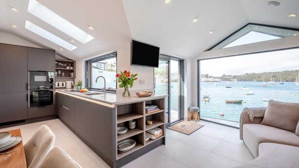 Una cucina moderna con isola centrale, elettrodomestici integrati e un'ampia finestra vista mare.