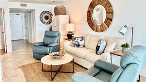 A living room with a ceiling fan, a round mirror, a sofa, a coffee table, and a chair.