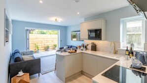 Een moderne keuken met een centraal eiland, een zithoek met een bank en uitzicht op het buitengebied.