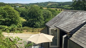 Een klein huis met een balkon met uitzicht op een prachtig landschap.