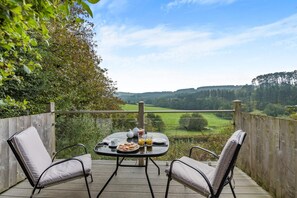 Una terraza con una mesa preparada para dos, con vistas a un paisaje pintoresco.