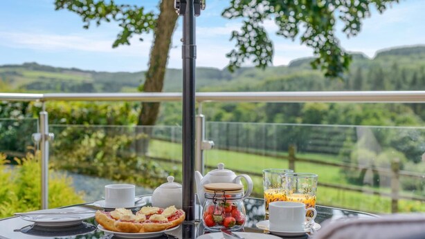 A table with breakfast items and a scenic outdoor view. - 1 Bed in Woodford (oc-o32064) (Woodford)