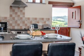 A kitchen with a view of the countryside, a dining area with chairs, and a breakfast setting. - 1 Bed in Woodford (oc-o32064) (Woodford)