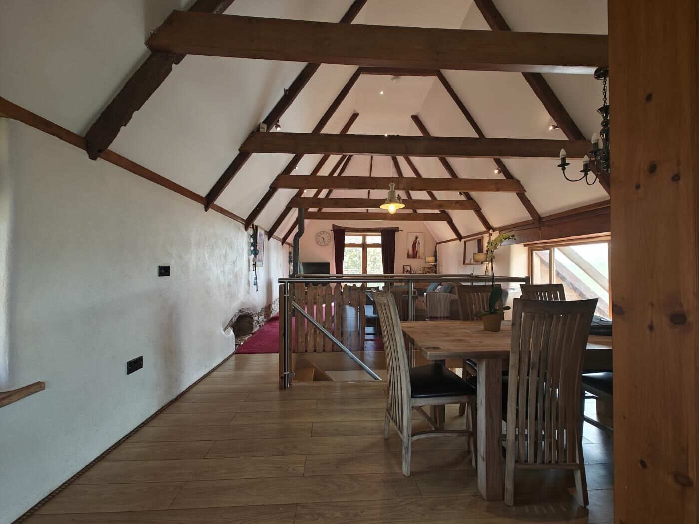 Ein geräumiges Dachzimmer mit Holzbalken, einem Essbereich mit Holzkästen und einem großen Fenster, das natürliches Licht hereinlässt.