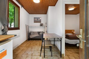 Une pièce de taille modeste comprenant un lit, une petite table, un banc, une fenêtre donnant sur un paysage agréable et un plafond en bois.