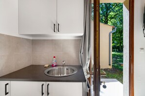 Een keuken met een spoelbak, kastjes en uitzicht op een tuin.