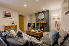 Un salon confortable avec un canapé, une table basse, une cheminée et un téléviseur.