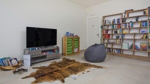 Olohuone, jossa on televisio, kirjahylly ja suuri eläimen nahasta valmistettu matto lattialla.