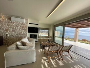 Ein modernes Wohnzimmer mit Steinwand, einer Couch, einem Fernseher und Meerblick.