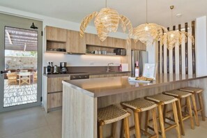 Eine moderne Küche mit Holzschränken, einer großen Kochinsel und Weidekorbstühlen.