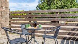 A patio area with a table and two chairs, a coffee pot, and a phone on the table.