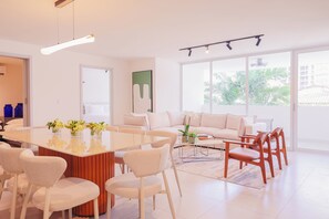A modern living room with a central dining table, white sofas, and wooden chairs. - Edificio Doña Raquel (Panama City)