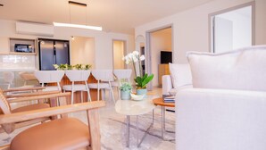 A modern living room with a sofa, chairs, a dining table, and potted plants. - Edificio Doña Raquel (Panama City)