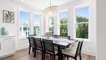 Un espace repas avec une grande table, des chaises noires et un lustre.