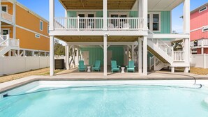 Una casa a due piani con una veranda coperta e una piscina.