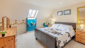 Een slaapkamer met een bed, nachtkastjes, een dressoir, een spiegel, een raam en een blauwe wandkast.