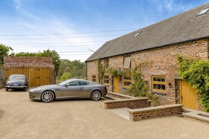 A brick building with a carport, a vintage car, and a modern sports car parked in front. - 7 Bed in Stoke-on-Trent (oc-t32196) (Stoke-on-Trent)