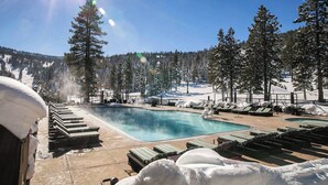 Un espace piscine avec des chaises longues et une vue sur un paysage enneigé.