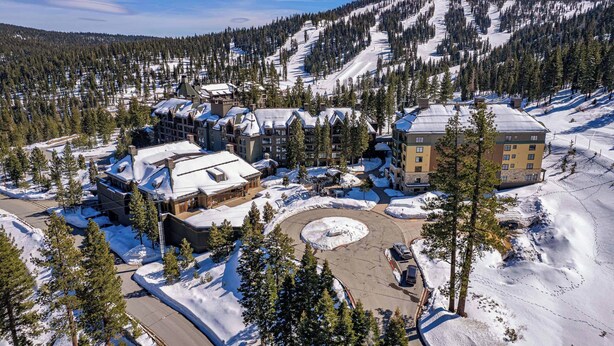 Une station de ski comprenant plusieurs bâtiments, un paysage enneigé et un décor montagneux.