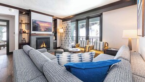 Un salon moderne avec une cheminée, un ensemble de canapés, une table basse et une grande fenêtre donnant sur un paysage enneigé.