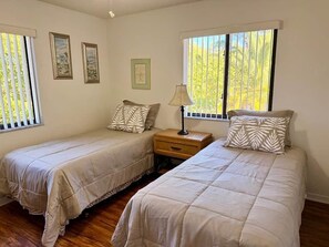 Une chambre avec deux lits, une table de chevet et une fenêtre avec des stores.