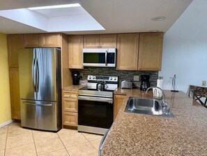 A modern kitchen with a stainless steel refrigerator, a microwave, an oven, and a sink.