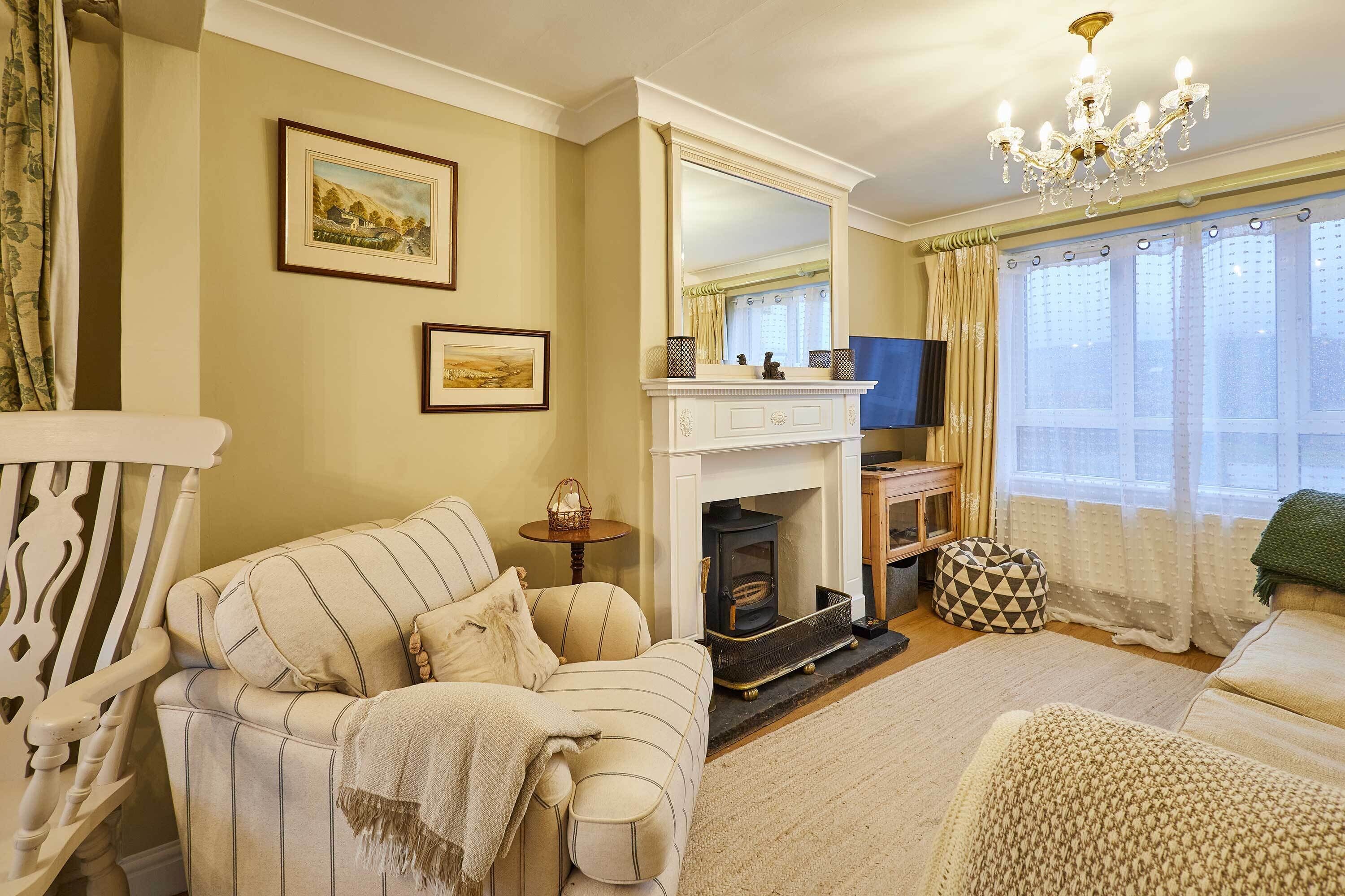 A cozy living room with a fireplace, a sofa, a television, and a chandelier.