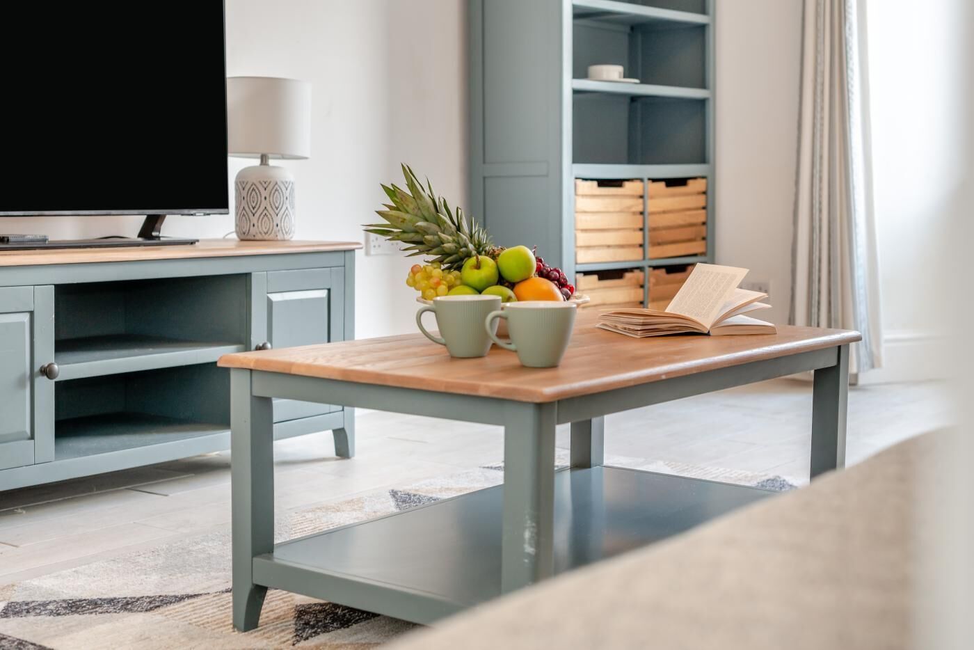 Een moderne woonkamer met een houten salontafel, een televisie en een boekenkast.