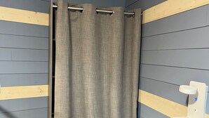A bathroom with a shower curtain, wooden panel walls, and a towel rack.