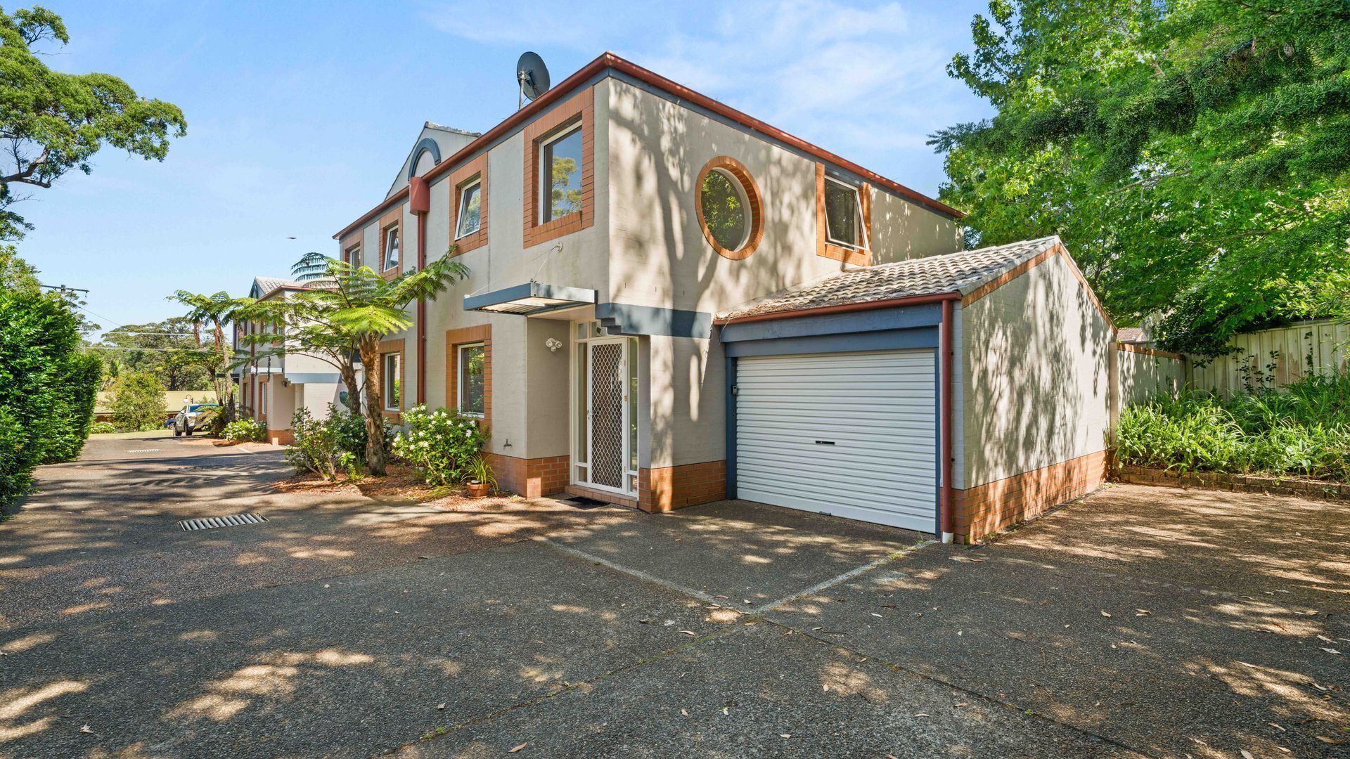 A two-story house with a garage, a satellite dish, and a driveway leading to the entrance.