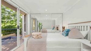 Ein modernes Schlafzimmer mit einem großen Bett, einem Balkon und einer Glastür zum Außenbereich.