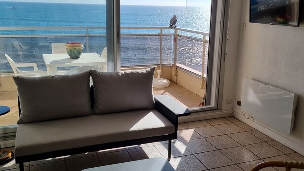 A balcony with a sofa, a table, and a chair. The balcony overlooks the sea. - Luxury Seafront Studio in Sables-d'Olonne (Les Sables-d'Olonne)