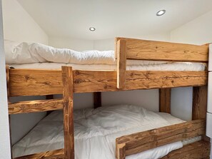 Ein Etagenbett mit Holzrahmen und weißer Bettwäsche.
