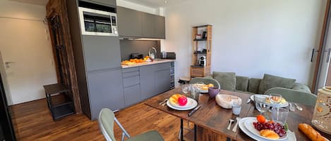 Une cuisine moderne avec des meubles gris, une table à manger en bois mise avec des assiettes, des verres et des couverts.