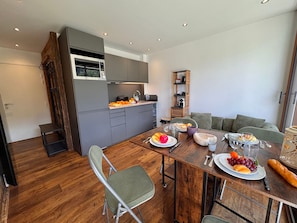 A modern kitchen with grey cabinets, a wooden dining table set with plates, glasses, and cutlery. - Cozy T2 at slopes' foot, Vars, 3 pers (Vars)