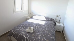 Een slaapkamer met een bed, twee nachtkastjes, een raam en een handdoek op het bed.