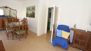 Ein Wohnzimmer mit Essbereich, einem blauen Sessel und einem Holzschrank.