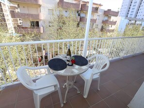 A balcony with two white plastic chairs and a small round table, a bottle, and a glass. - Spacious Apartment Near Salou Beach – Perfect for Families & Groups (Salou)